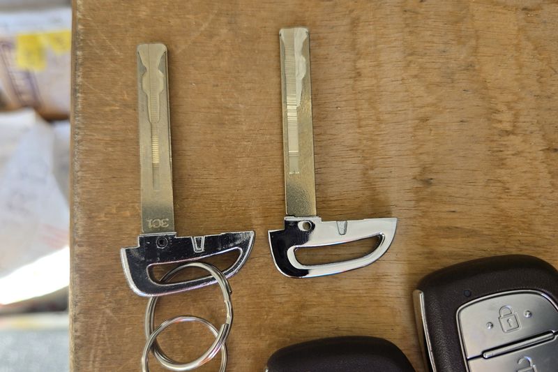 Two Hyundai smart keys and their cut emergency blades laid out on a wooden bench.