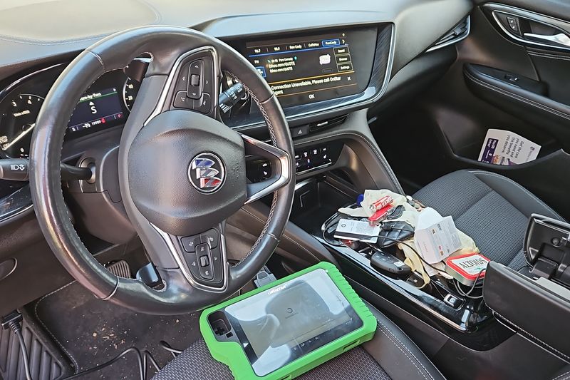 Key programming equipment on the seat of a Buick while a replacement key is coded to the car.