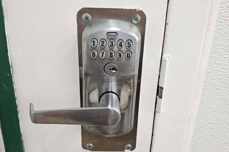 A keypad lever lock installed on a white commercial door.