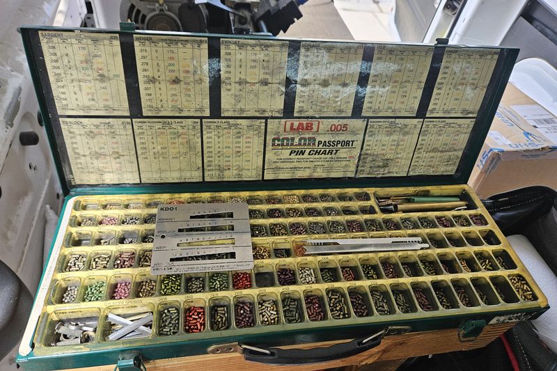 An open locksmith pinning kit with color-coded pin trays and a LAB pin chart, used for rekeying locks.